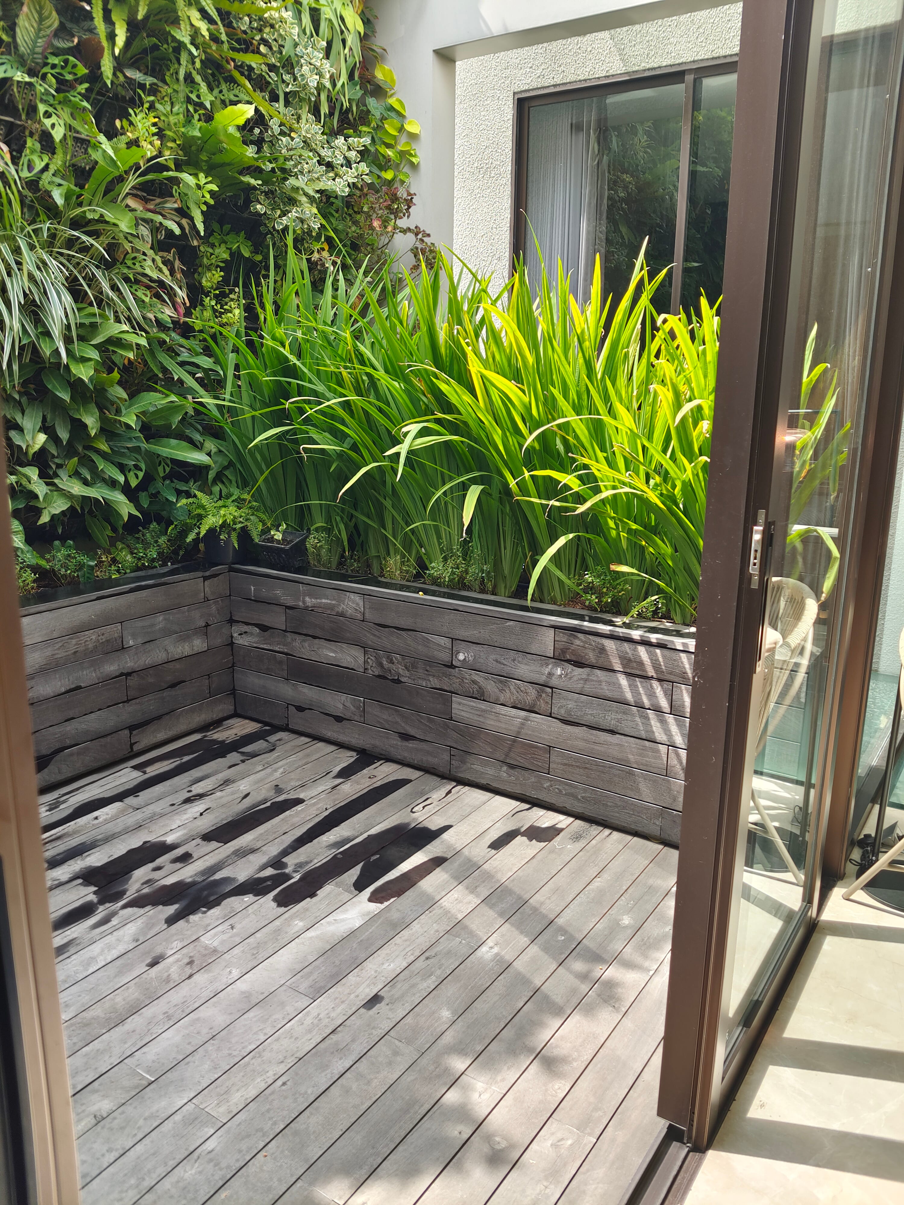 Outdoor hardwood deck terrace with dark timber-clad L-shaped planter box and vertical garden at JGC private residence by Reywood