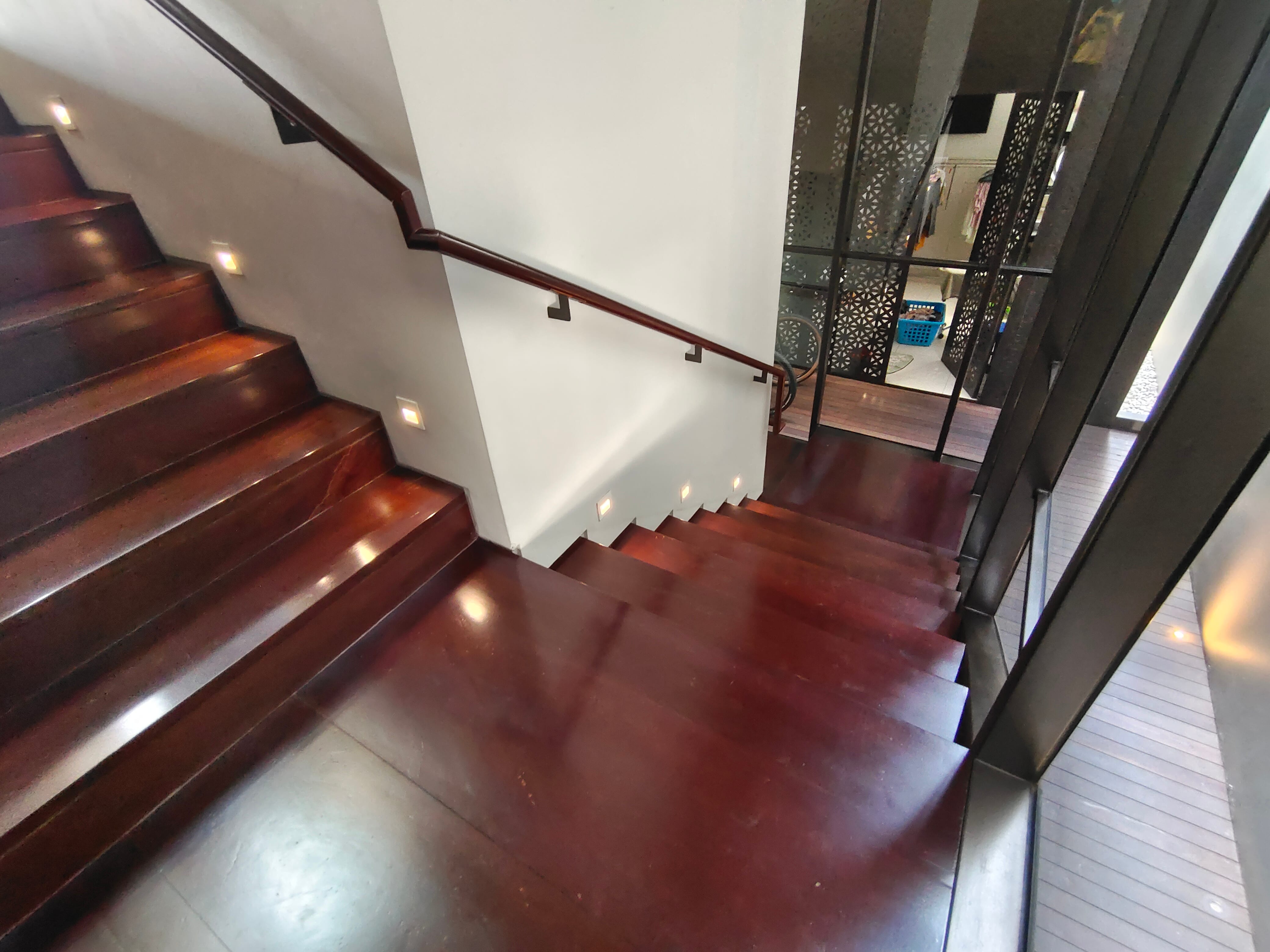 Solid wood staircase viewed from above showing dark hardwood treads, risers, and matching landing floor with recessed step lights at JGC residence by Reywood