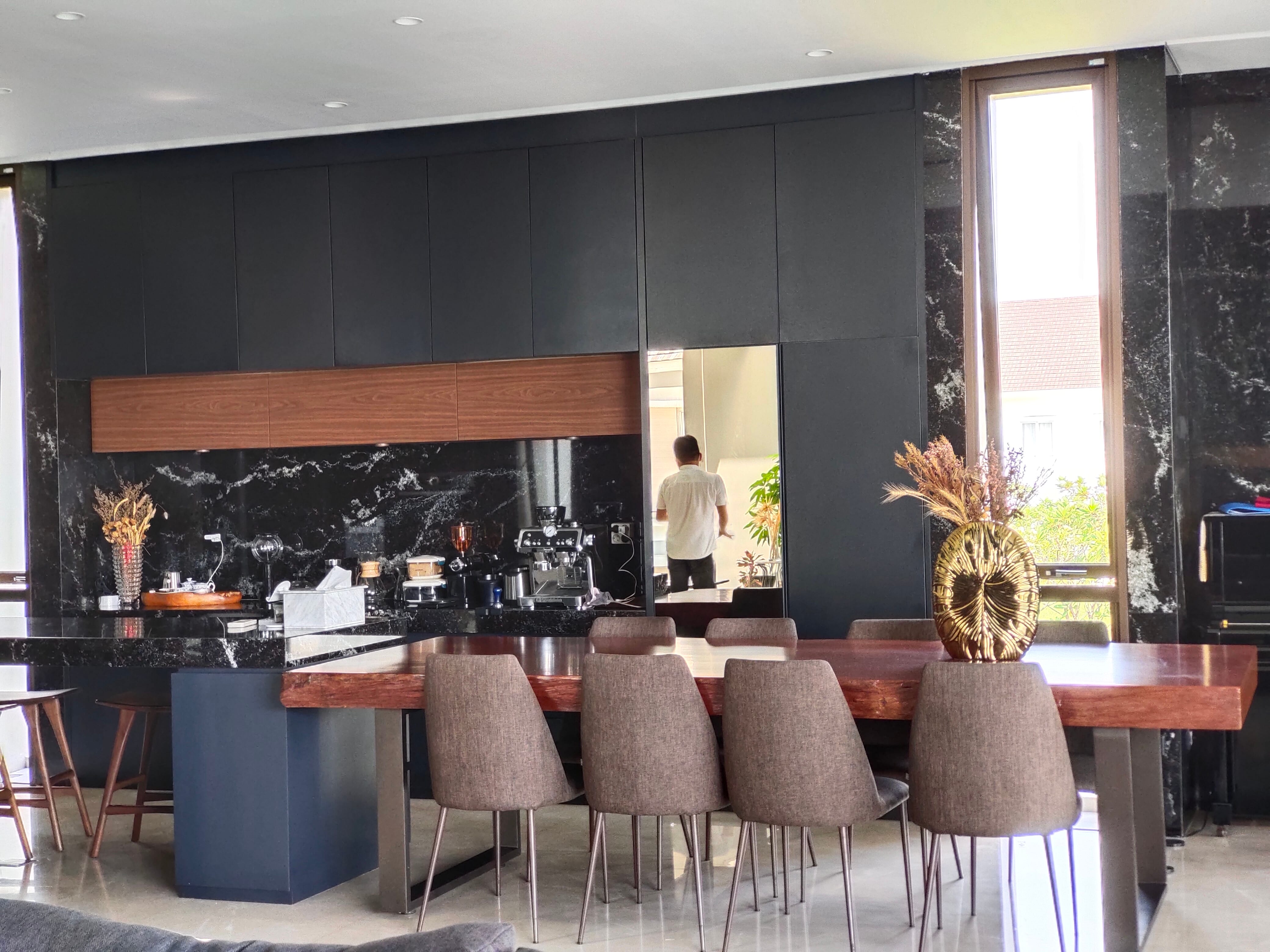 Solid wood dining table with eight chairs and wood accent cabinetry band in the open kitchen and dining zone at JGC by Reywood